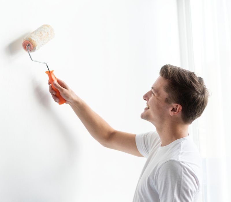 smiling guy painting wall with roller