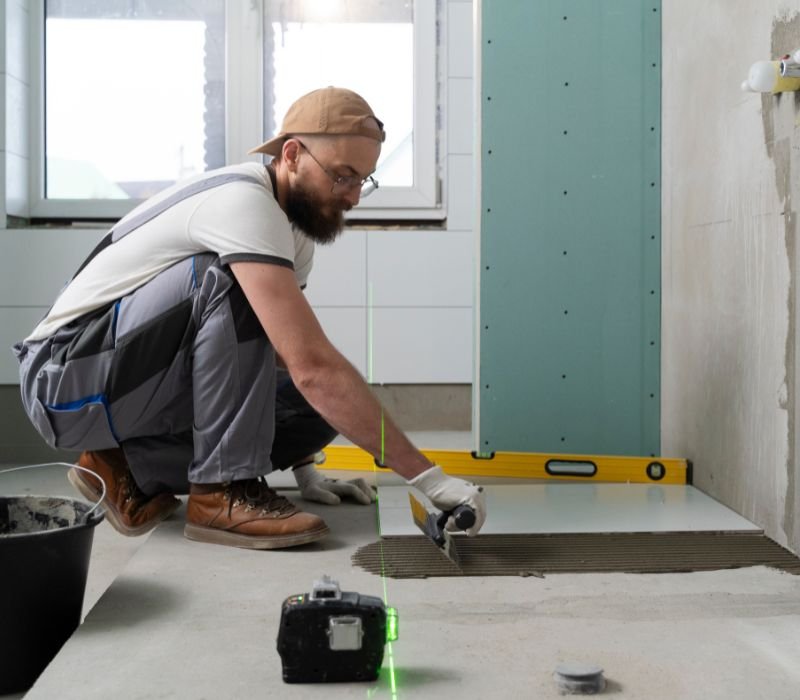 a mason applying tiles in bathroom