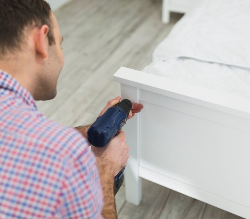 a boy is drilling side of bed to repair