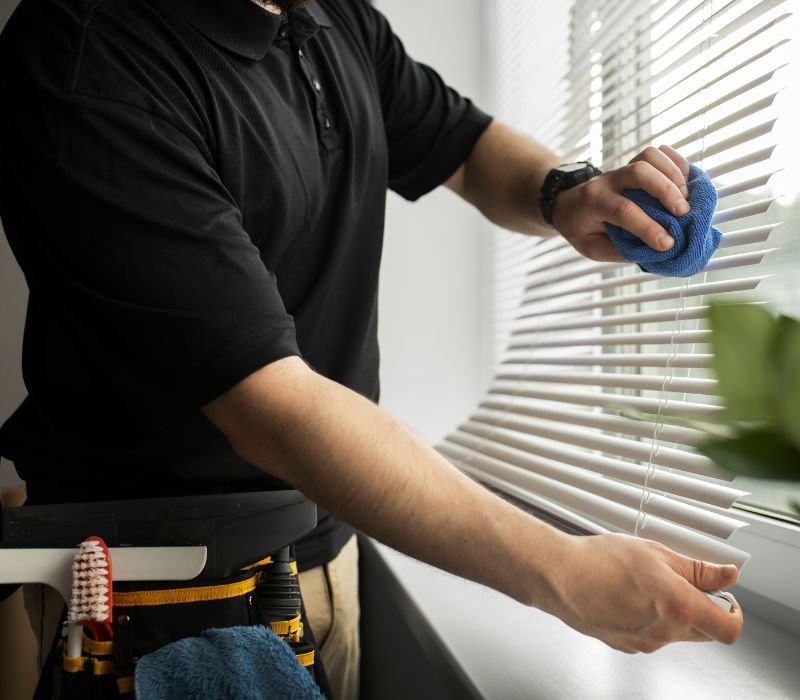 a man is cleaning blinds with cloth after installation