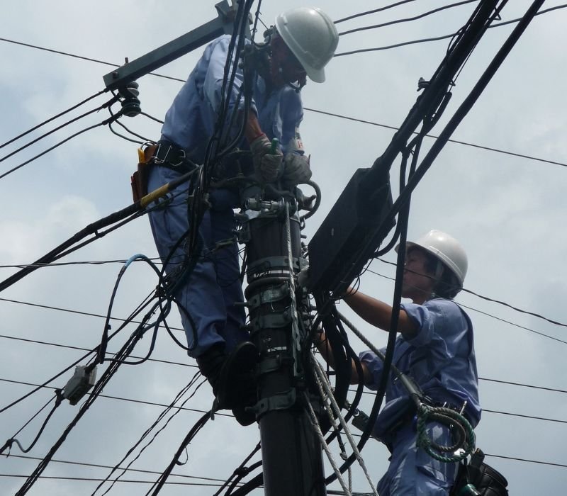 two electricians repairing electricity on pole in emergency