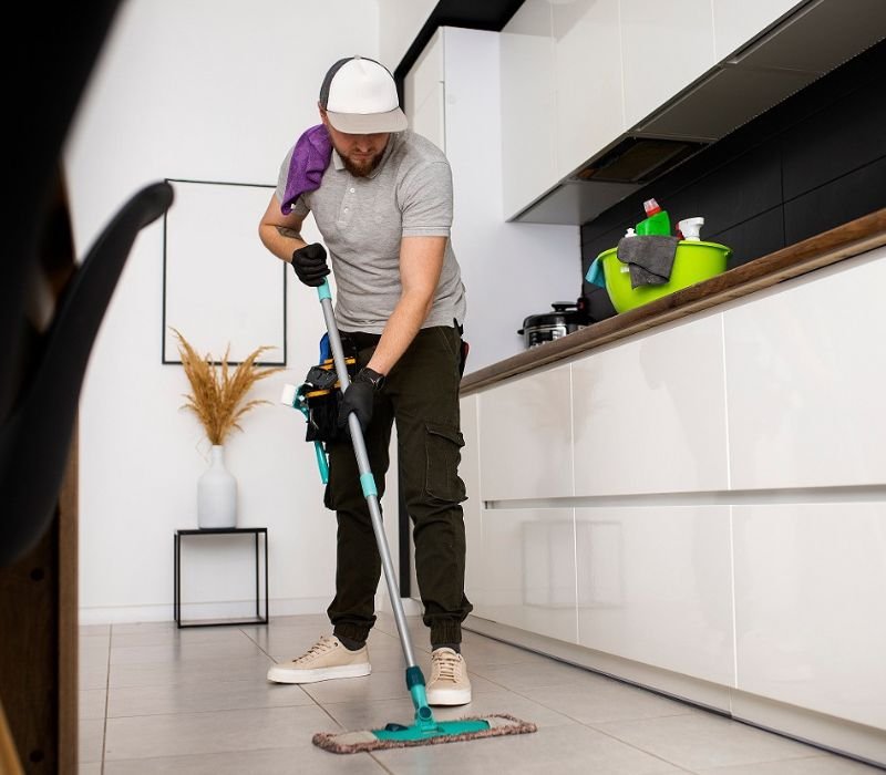 a boy cleaning kithen floor with mop