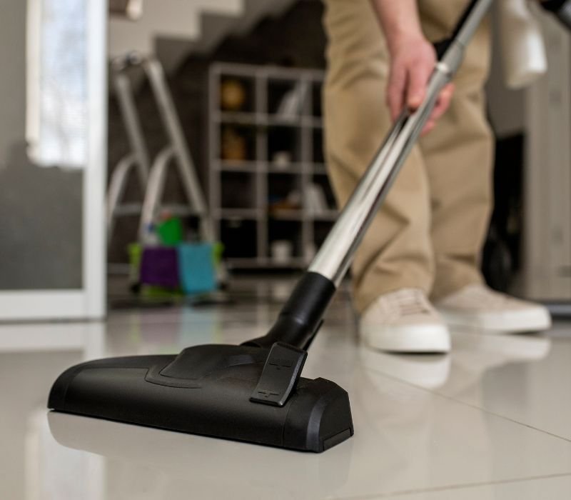 a male is cleaning villa floor with vacuum